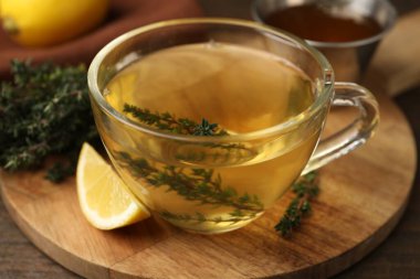 Cam bardakta taze kekik çayı ve ahşap masada bir dilim limon, yakın plan.