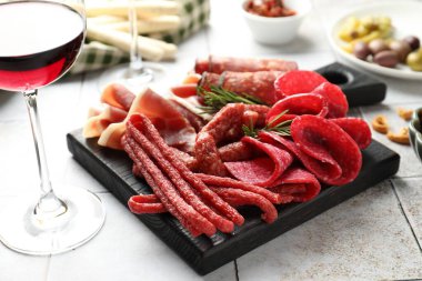 Şarküteri tahtası, farklı pişirilmiş et, sosis ve şarap beyaz fayanslı masada, yakın plan.