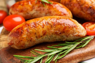 Lezzetli ızgara sosis, domates ve biberiye masada, yakın plan.