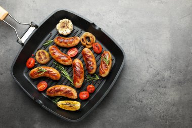 Izgara sosis, domates ve biberiye gri masada ızgara tavada servis edilir. Metin için boşluk