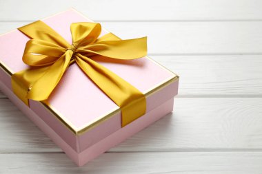 Beyaz ahşap masa üzerinde fiyonklu güzel bir hediye kutusu, yakın plan. Metin için boşluk