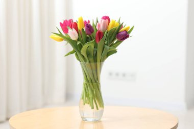 İçerideki ahşap masada vazoda renkli laleler.