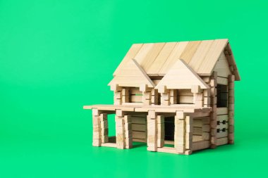 Yeşil arka planda tahta bloklardan yapılmış bir ev. Metin için boşluk