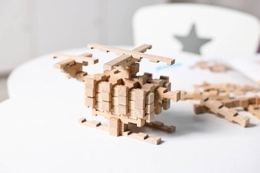 Beyaz masadaki ahşap bloklardan yapılmış helikopter figürü.