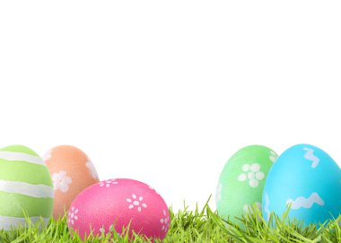 Beyaz arka plana karşı yeşil çimlerde paskalya yumurtaları