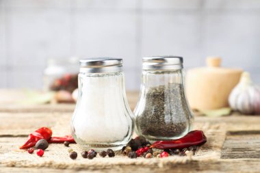 Ahşap masaya baharatlı tuzluk ve biberlikler seramik duvara karşı, yakın plan.