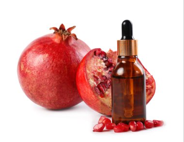 Beyaz üzerine izole edilmiş bir şişe temel yağ ve taze nar.