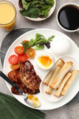 Gri masada servis edilen kaynamış yumurta ve pastırmalı lezzetli bir kahvaltı.