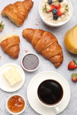 Nefis bir kahvaltı. Lezzetli kruvasanlar, reçeller, böğürtlenler, yulaf ezmesi ve içecekler açık gri masada, düz yatıyordu.