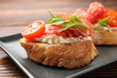 Salamlı, krem peynirli, ahşap masadaki domatesli nefis bruschettalar.