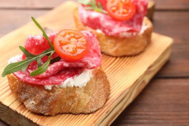 Salamlı, krem peynirli, ahşap masadaki domatesli nefis bruschettalar.