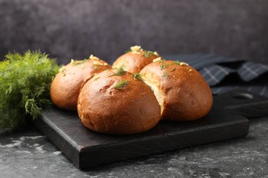 Siyah masada sarımsaklı taze çörekler ve dereotlar, yakın plan.