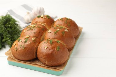 Sarımsaklı taze çörekler ve beyaz ahşap masada dereotlar, yakın plan.