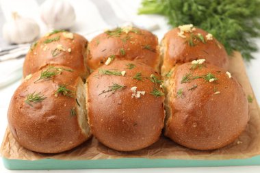 Beyaz masada sarımsaklı taze çörekler ve dereotlar, yakın plan.