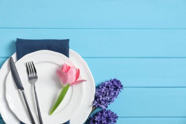 Açık mavi ahşap arka planda çiçek dekoru olan şık masa dekorları, düz yatış. Metin için boşluk