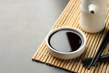 Soya sosu kasede ve çubuklar gri masada, yakın plan. Metin için boşluk