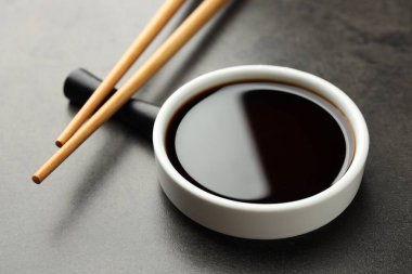 Soya sosu kasede ve çubuklar gri masada, yakın plan.