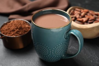 Bardakta nefis kakao, fasulye ve pudra gri masada, yakın plan.