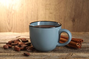 Bardakta nefis kakao, fasulye ve tarçın çubukları ahşap masada, yakın plan.