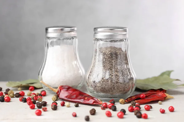 Açık gri masada baharatlı tuzluk ve biberlikler, yakın plan.