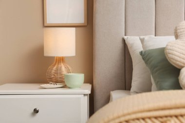 Şık lamba, fincan ve yüzükler evdeki komodinin yanında.