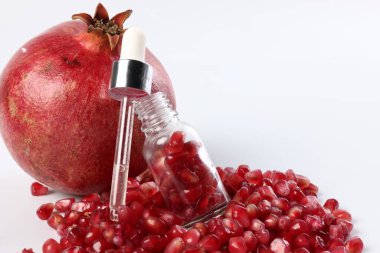 Tohumlu şişe, pipetli ve beyaz zemin üzerinde taze nar, yakın plan.