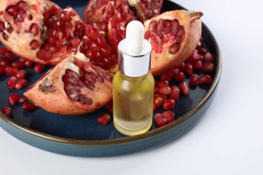 Beyaz zemin üzerinde gerekli yağ ve taze nar şişesi, yakın plan.