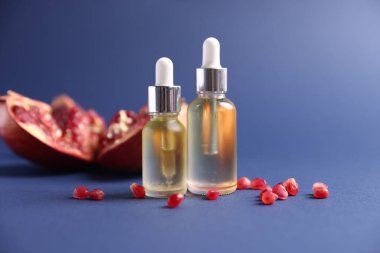 Mavi arka planda gerekli yağ ve taze nar şişeleri, yakın plan.