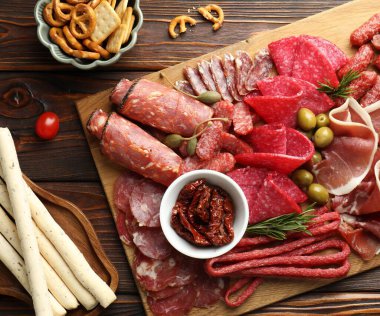 Şarküteri tahtası, farklı pişirilmiş et, sosis ve ahşap masa üzerinde zeytin, düz yatıyordu.