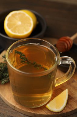 Aromatic thyme tea in cup, lemon and honey on table, closeup