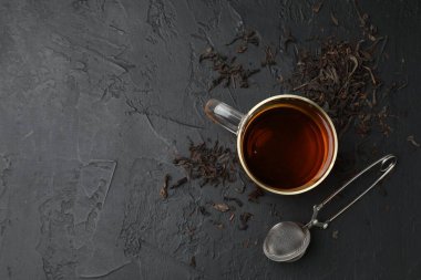 Bir fincan çay, kuru yapraklar ve siyah masada metal infüzyon. Metin için boşluk