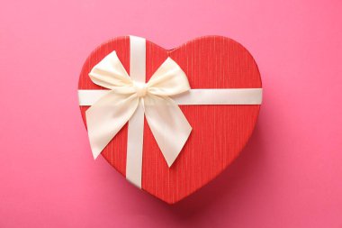 Pembe arka planda güzel kalp şeklinde bir kutu, üst manzara.