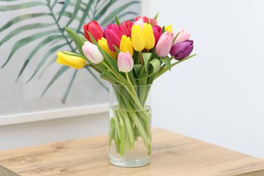 İçerideki ahşap masada vazoda renkli laleler.