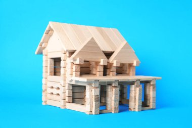 Açık mavi arka planda tahta bloklardan yapılmış ev