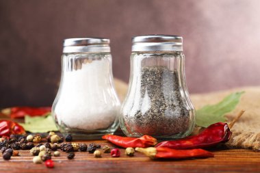 Ahşap masada baharatlı tuzluk ve biberlikler, yakın plan.