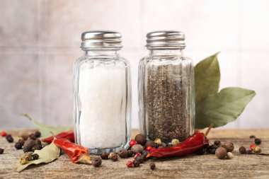Ahşap masada baharatlı tuzluklar ve biberlikler bulanık arka planda, yakın plan