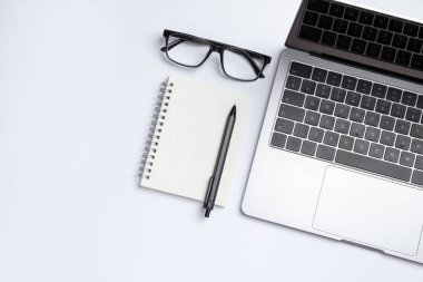 Laptop, kırtasiye malzemesi ve beyaz arka planda gözlük, düz konum. Metin için boşluk