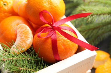 Mandalinalar sandıkta ve köknar dalları masada, yakın plan.