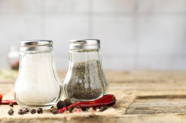 Ahşap masada duvarlara karşı baharatlı tuzluk ve biberlikler, yakın plan. Metin için boşluk