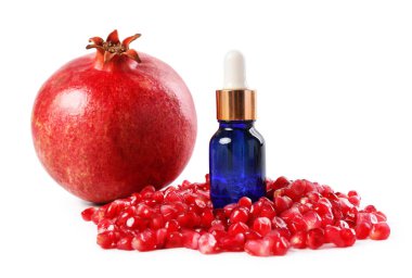 Bir şişe gerekli yağ, taze nar ve beyaz üzerine izole edilmiş tohumlar.
