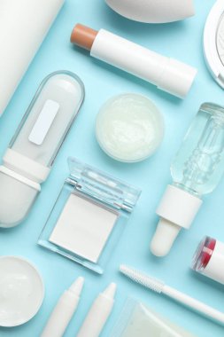Açık mavi arka planda farklı makyaj ürünleri, düz yatış