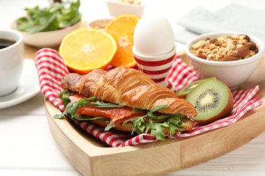 Sağlıklı kahvaltı. Beyaz ahşap masada somon, meyve, yumurta ve yulaf ezmeli lezzetli kruvasan, yakın plan.