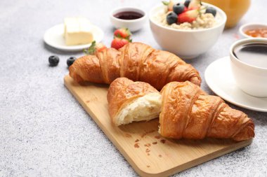 Nefis bir kahvaltı. Lezzetli kruvasanlar, böğürtlenler, yulaf ezmesi ve kahve açık gri masada, yakın plan.