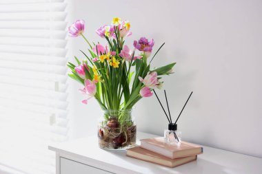 Vazoda güzel bahar çiçekleri, kitaplar ve sazlıklar pencerenin yanındaki şifoniyerde, metin için boşluk