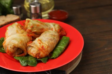 Yummy stuffed cabbage rolls served on wooden table, closeup. Space for text