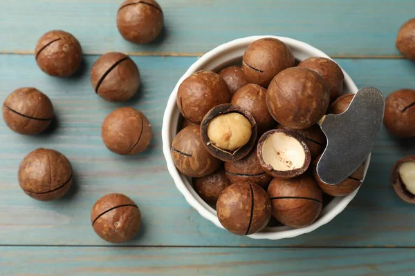 Macadamia fındığı ve metal anahtar açık mavi ahşap masada, düz yerde.