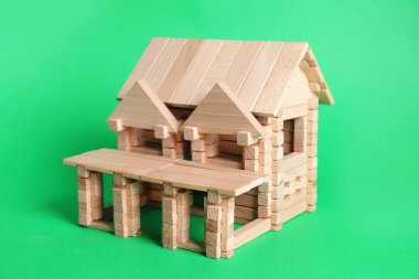 Yeşil arka planda tahta bloklardan yapılmış bir ev.