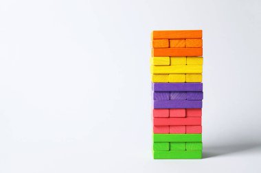 Işık arka planında renkli bloklardan oluşan bir kule. Metin için boşluk