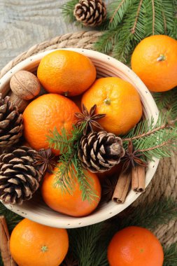 Olgun mandalinalar, baharatlar, koniler, cevizler ve ağaç dalları ahşap masa, üst görünüm