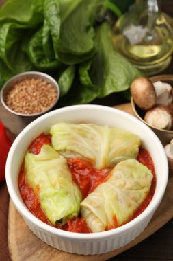 Lezzetli dolgulu lahana ruloları ve malzemeler masada, yakın plan.